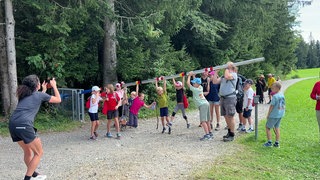 Unterwegs auf dem Schmugglerpfad in Oberreute. Kinder spielen an einem Schlagbaum.