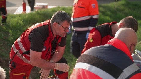 Notarzt Björn Hossfeld kniet mit anderen Rettungskräften an einer Unfallstelle.