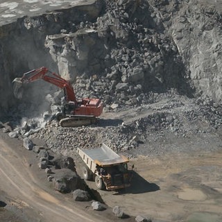 Es wird mit einem Bagger und einem LKW in einem Steinbruch gearbeitet