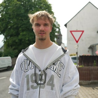 Mann im grauen Pullover steht auf der Straße