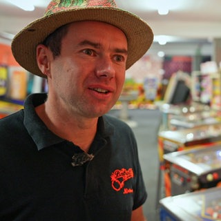 Mann steht vor Pinball-Maschinen.