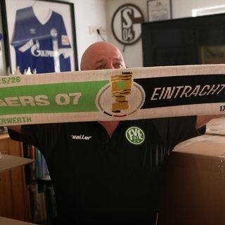 Mann hält Fußballschal in die Kamera