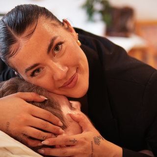 Junge Frau streichelt ältere Frau im Krankenbett