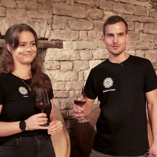 Mann und Frau stehen vor einem Weinfass