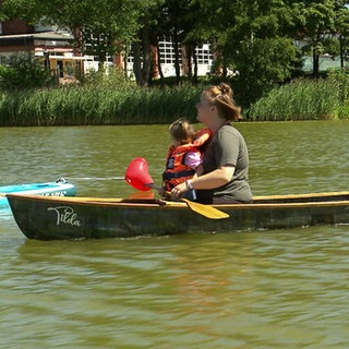 Ein Kanu fährt mit drei Personen auf dem Wasser