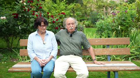 Emil Völker und Gwenlyn Völker-McNeil sitzen auf einer Bank in ihrem Garten.