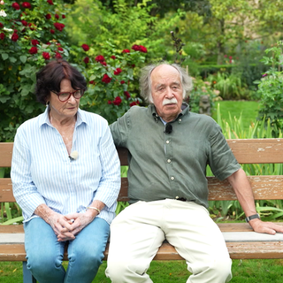 Emil Völker und Gwenlyn Völker-McNeil sitzen auf einer Bank in ihrem Garten.