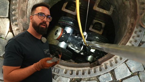 Mann steht vor einem Kanalroboter