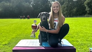 Frau sitzt mit Hund auf einem Siegertreppchen