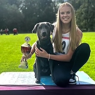 Frau sitzt mit Hund auf einem Siegertreppchen