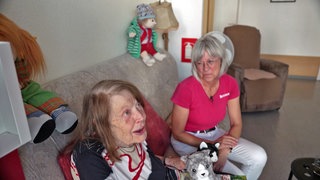 Die Leiterin der Tagespflege Kastellaun, Susanne Kunz (r.), schaut lächelnd auf eine ihrer Besucherinnen