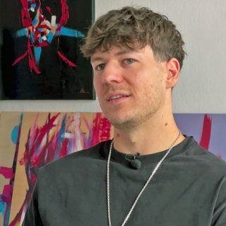 Künstler Fabian Utta vor einigen seiner Bilder