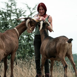 Frau füttert Ziegen im Freien