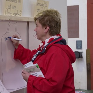 Eine Frau schreibt etwas auf ein Plakat zum Thema Glocken