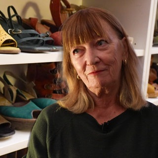 Frau steht vor einem Bücherregal voller Schuhe