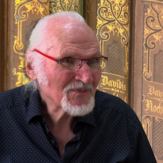 Mann ist vor alten Kochbüchern abgebildet