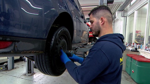 Ein Mechaniker wechselt in einer Werkstatt einen Reifen an einem Auto