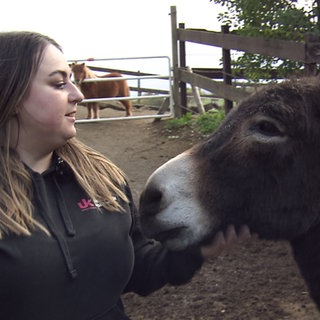 Frau streichelt einen Esel