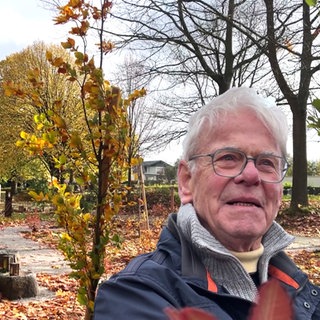 Der Friedgarten in Dernbach im Hintergrund und Karl-Heinz Ferrai.