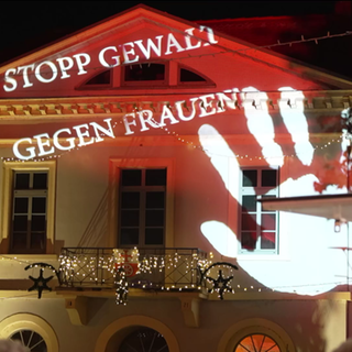 'Stopp Gewalt gegen Frauen' an eine Hauswand projiziert