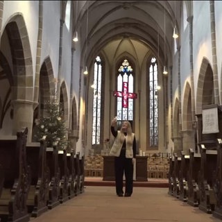 Eine Pfarrerin steht in einer Kirche in Landau und macht ein Video