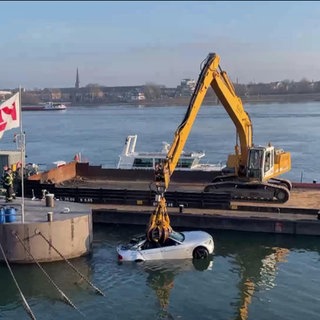 Ein Kran zieht ein Auto aus dem Rhein