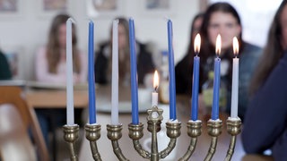 Junge Frauen sind verschwommen durch einen achtarmigen Kerzenleuchter zu sehen