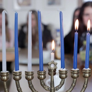 Junge Frauen sind verschwommen durch einen achtarmigen Kerzenleuchter zu sehen