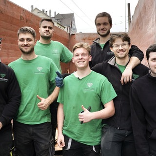 Das junge Team der Entrümplungsfirma Diamclean steht vor einer Hauswand.