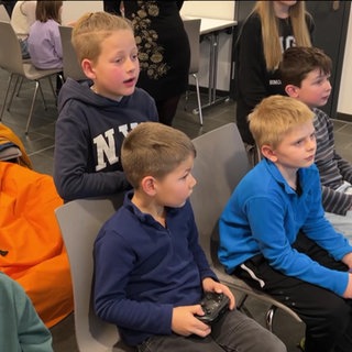 Kinder spielen in einer Bücherei an Konsolen