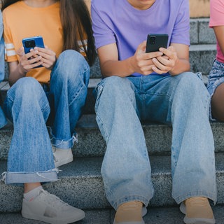 Kinder sitzen mit Mobiltelefonen auf einer Treppe