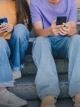 Kinder sitzen mit Mobiltelefonen auf einer Treppe
