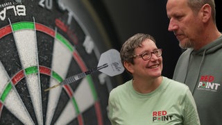 Das Paar Antje Miklo und ihr Lars Schröder vor einer Dartscheibe