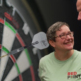 Das Paar Antje Miklo und ihr Lars Schröder vor einer Dartscheibe