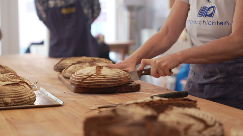 Frisch gebackene Sauerteigbrote aus dem Backkurs werden von Bäckerin Verena Rappaport aufgeschnitten und getestet.