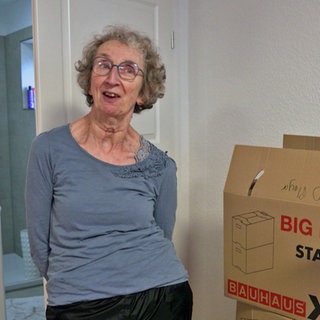Ute Jantzer ist an Parkinson erkrankt und steht neben Umzugskartons in ihrem neuen Zuhause der Starck-Stiftung in Schweighofen