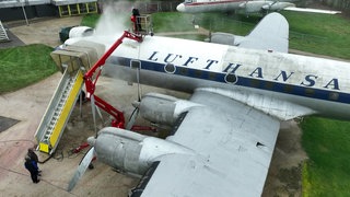 Person mit Luftdruckreiniger auf einem Flugzeug