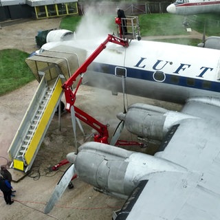 Person mit Luftdruckreiniger auf einem Flugzeug