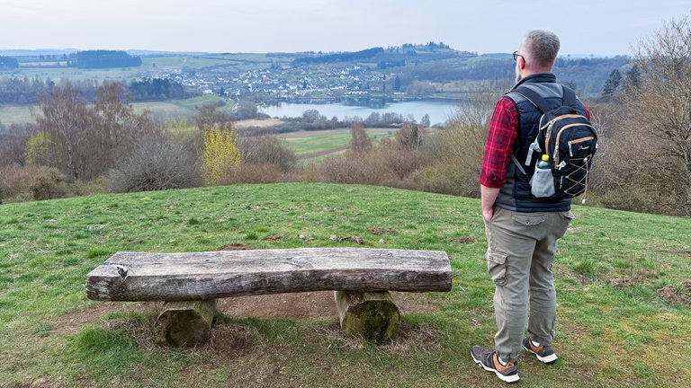 Mann an Bank mit Blick auf Schalkenmehrener Maar