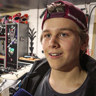 Jugendlicher steht in einer Motorrad-Werkstatt