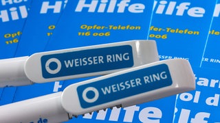 Auf zwei Kugelschreibern ist das blaue Logo des Weißen Ring zu sehen.