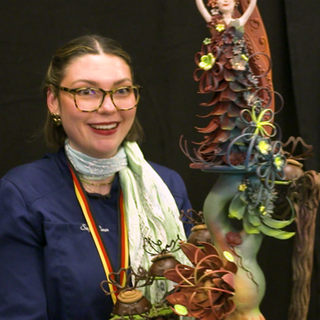 Soraya Romen ist eine junge Frau, die vor sich ihr Schokoladenkunst-Schaustück präsentiert.