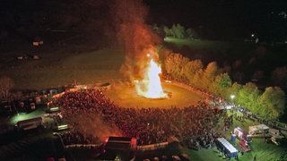 Bis zu 4.000 Gäste stehen um das riesige Maifeuer in Alpenrod herum