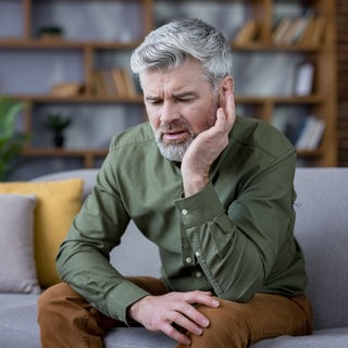 Mann hält sich schmerzend am Ohr