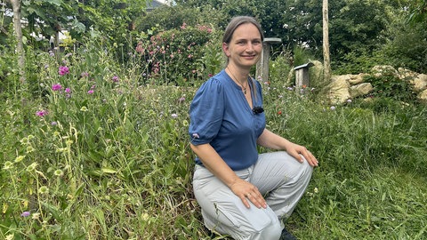 Frau sitzt in einem Wildbienengarten