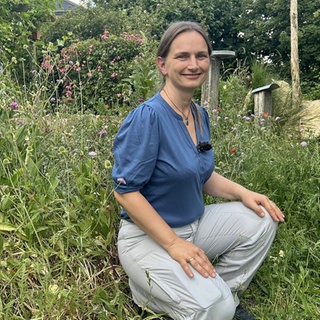 Frau sitzt in einem Wildbienengarten