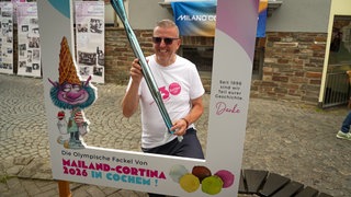 Mann steht mit einer olympischen Fackel in Cochemer Innenstadt.