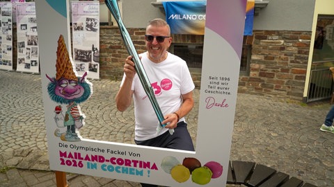 Mann steht mit einer olympischen Fackel in Cochemer Innenstadt.