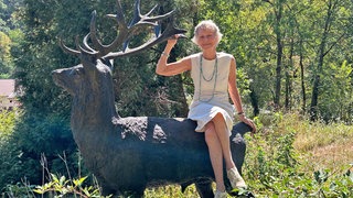 Marion von Gienanth auf einer Hirsch-Statue im Landschaftspark Friedrich von Gienanth in Eisenberg