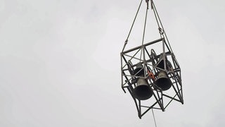 Kirchenglocken schweben an einem Kran durch die Luft